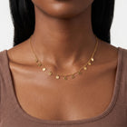 Close-up of the Lelice Penny Charm Necklace in gold at the collarbone