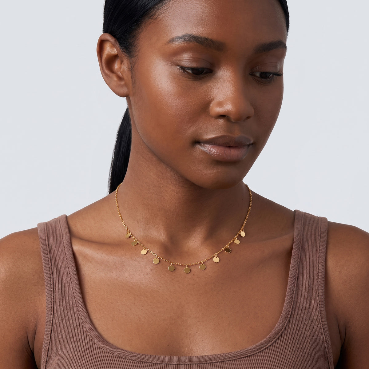Woman looking down at the Penny Charm Necklace