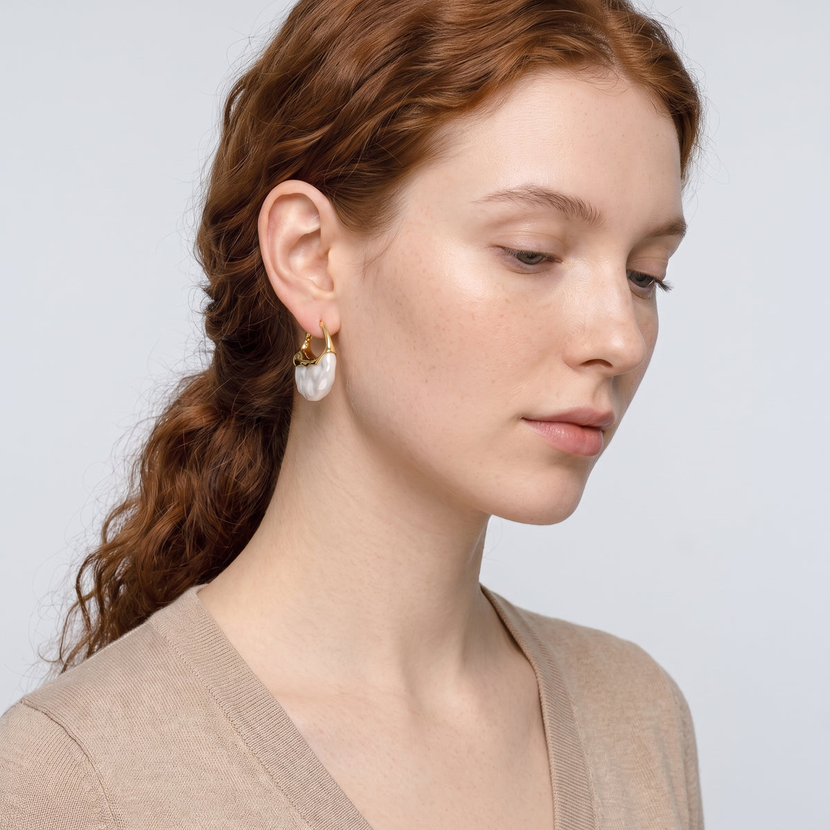 Model wearing the Lelice Perla Gold Baroque Pearl Chunky Hoop Earrings, serene chin lift