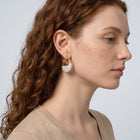 Model wearing the Lelice Perla Gold Baroque Pearl Chunky Hoop Earrings, sculpted side profile