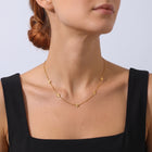 Low-angle portrait of a woman wearing the Petite Blossom Necklace