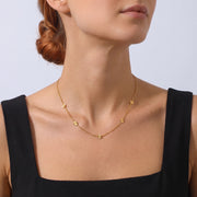 Low-angle portrait of a woman wearing the Petite Blossom Necklace