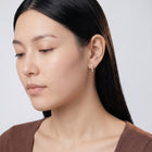 Model wearing the Lelice Petite Luxe Huggies in gold, downcast beauty portrait