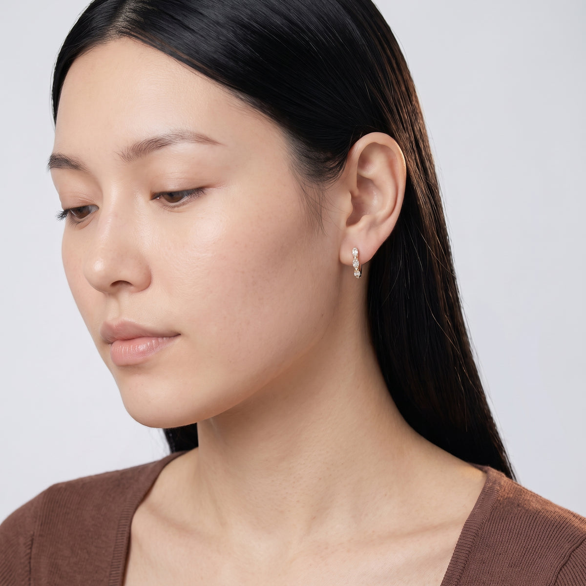 Model wearing the Lelice Petite Luxe Huggies in gold, downcast beauty portrait