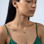 Three-quarter profile of a woman wearing the Piper Emerald Necklace