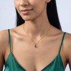 Woman with head tilted down wearing the Piper Emerald Necklace