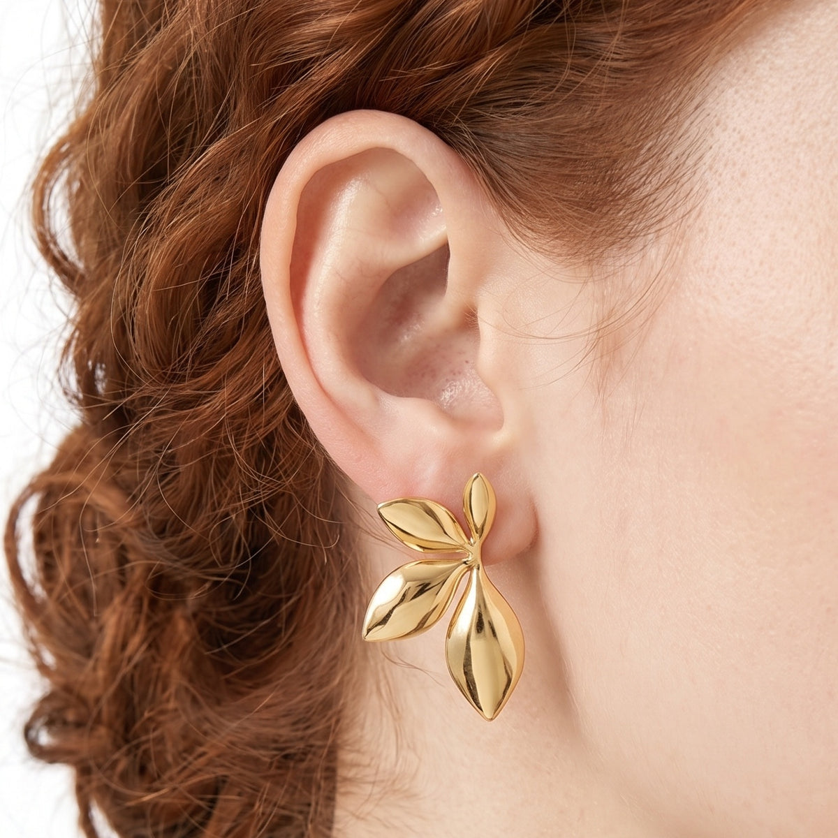 Close-up of the Lelice Puffy Petal Statement Studs in gold on the ear