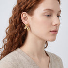 Model wearing the Lelice Puffy Petal Statement Studs in gold, serene chin lift