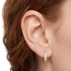 Close-up of the Lelice Remi Huggie Hoops in gold on the ear