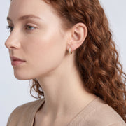 Model wearing the Lelice Remi Huggie Hoops in gold, sculpted side profile