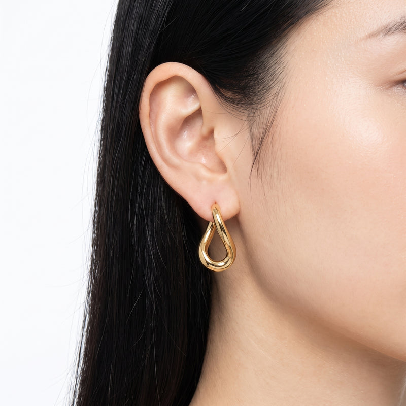 Close-up of ear wearing Lelice gold twisted teardrop hoop earrings Romy
