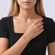 Model wearing the Lelice Ruby Crystal Bracelet in gold, hand at the collar