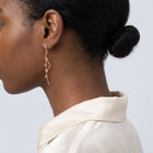 Model wearing the Lelice Santorini Blush Drops in gold, low bun, ear and neck