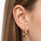 Close-up of the Lelice Sarah Minimal Hoops in gold on the ear