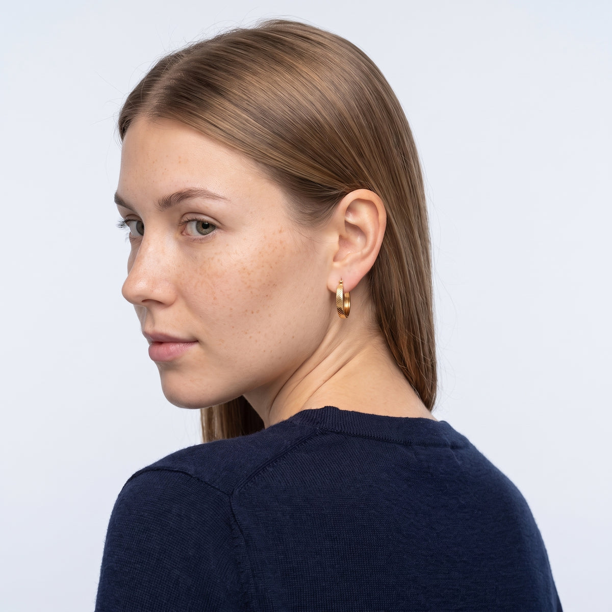 Model wearing the Lelice Sarah Minimal Hoops in gold, over-the-shoulder glance