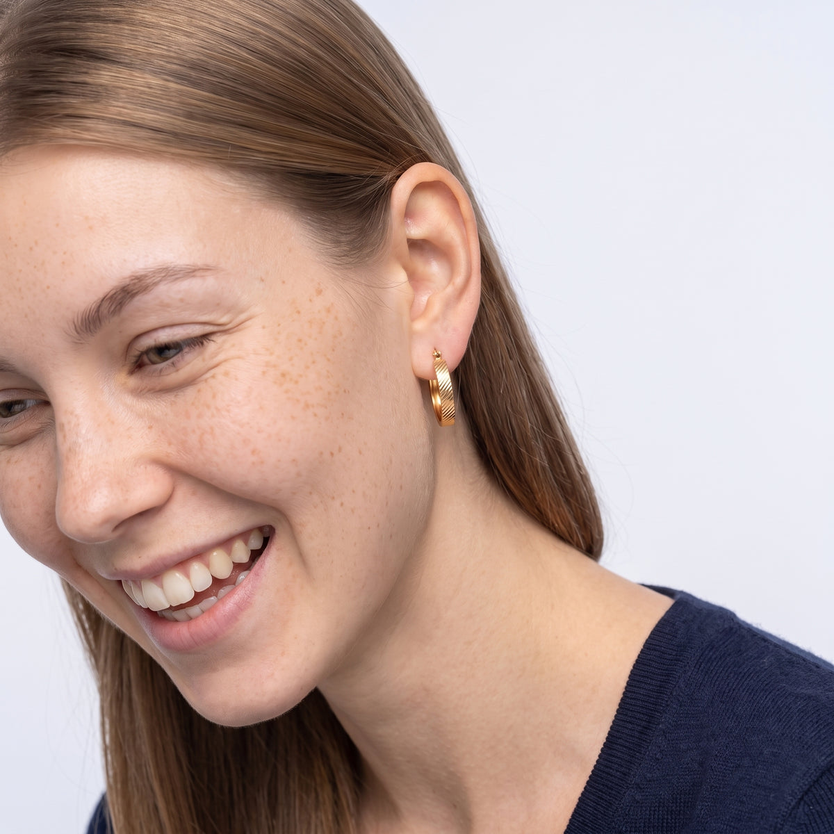 Model wearing the Lelice Sarah Minimal Hoops in gold, candid laugh