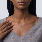 Hand at the collar of a woman wearing the Seraphina Opal Necklace
