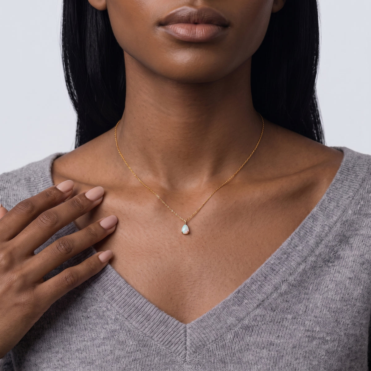 Hand at the collar of a woman wearing the Seraphina Opal Necklace