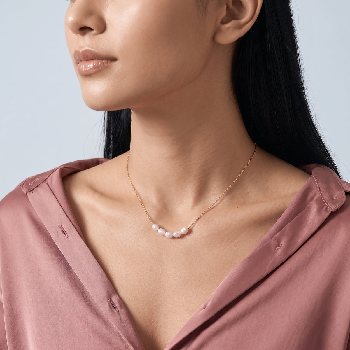 Three-quarter profile of a woman wearing the Siena Pearl Necklace