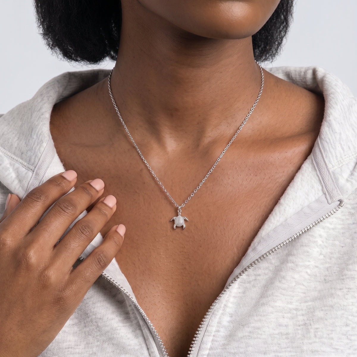 Hand at the collar of a woman wearing the Slow & Steady Silver Necklace
