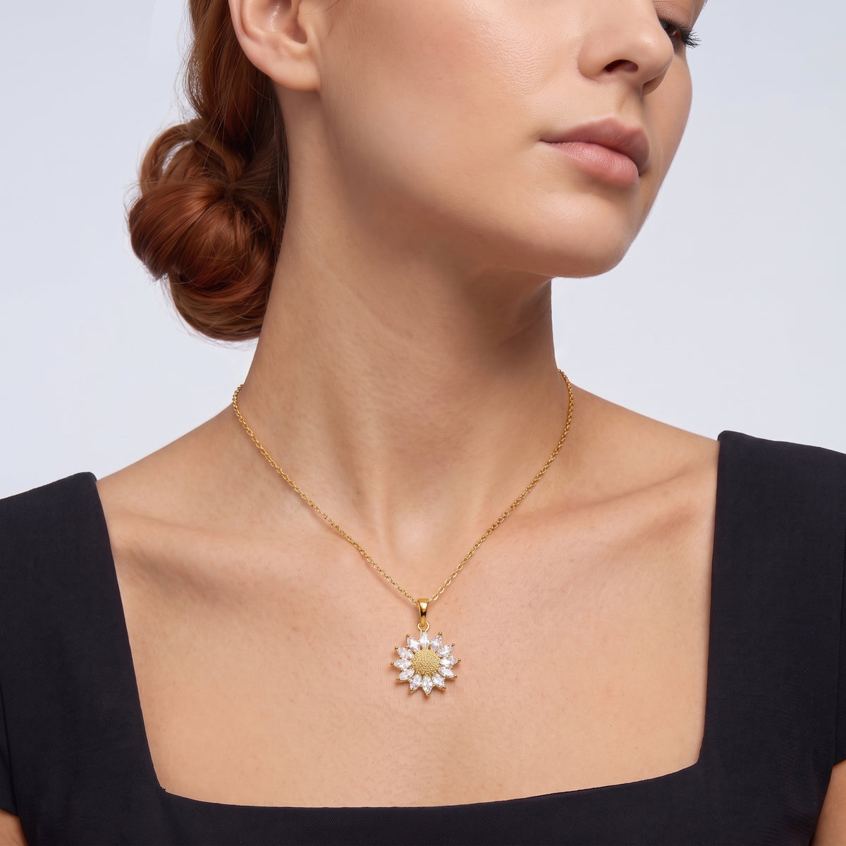 Low-angle portrait of a woman wearing the Soleil Gold Sunflower Pendant Necklace