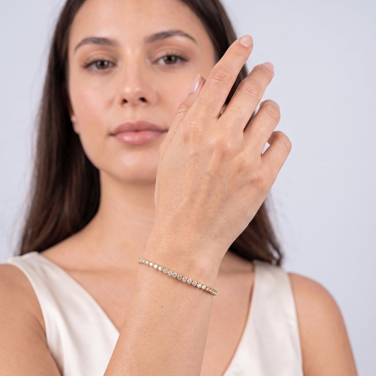 Model wearing the Lelice Sophie Tennis Bracelet in gold, hand in front of the face