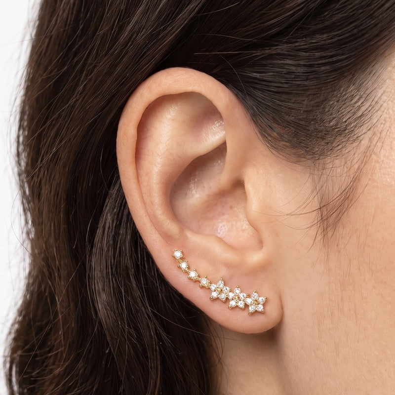 Close-up of the Lelice Stella Gold Flower and Star Crystal Ear Climbers on the ear