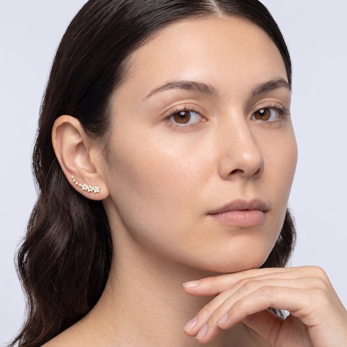 Model wearing the Lelice Stella Gold Flower and Star Crystal Ear Climbers, hand at the chin