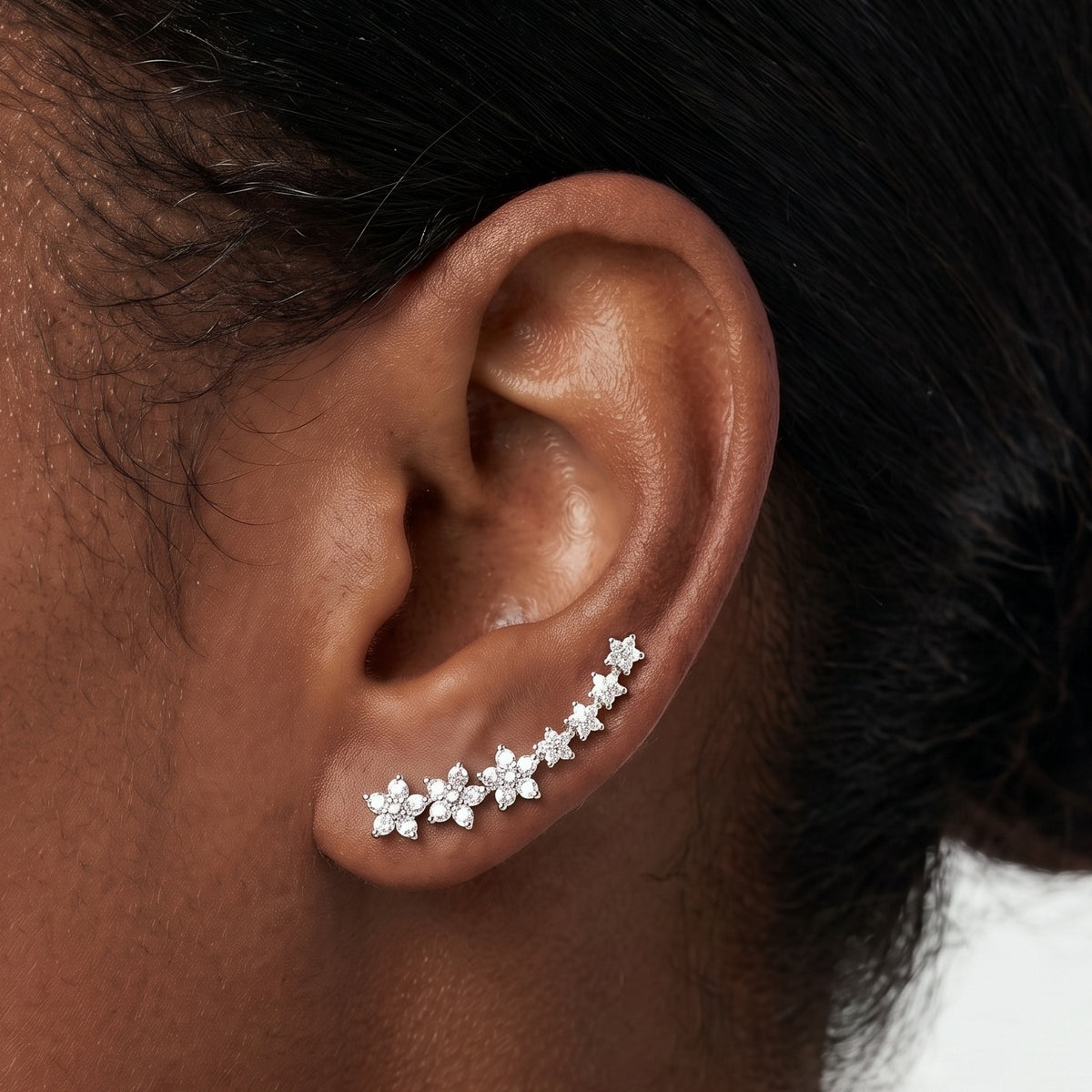 Close-up of the Lelice Stella Silver Flower and Star Crystal Ear Climbers on the ear