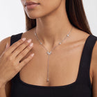 Hand at the collar of a woman wearing the Sunburst Lariat Silver Necklace