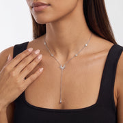 Hand at the collar of a woman wearing the Sunburst Lariat Silver Necklace