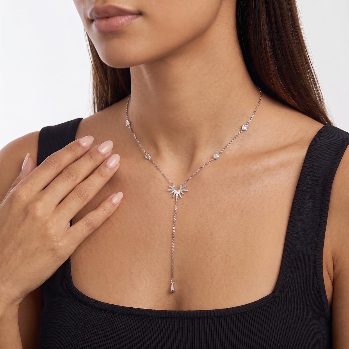 Hand at the collar of a woman wearing the Sunburst Lariat Silver Necklace