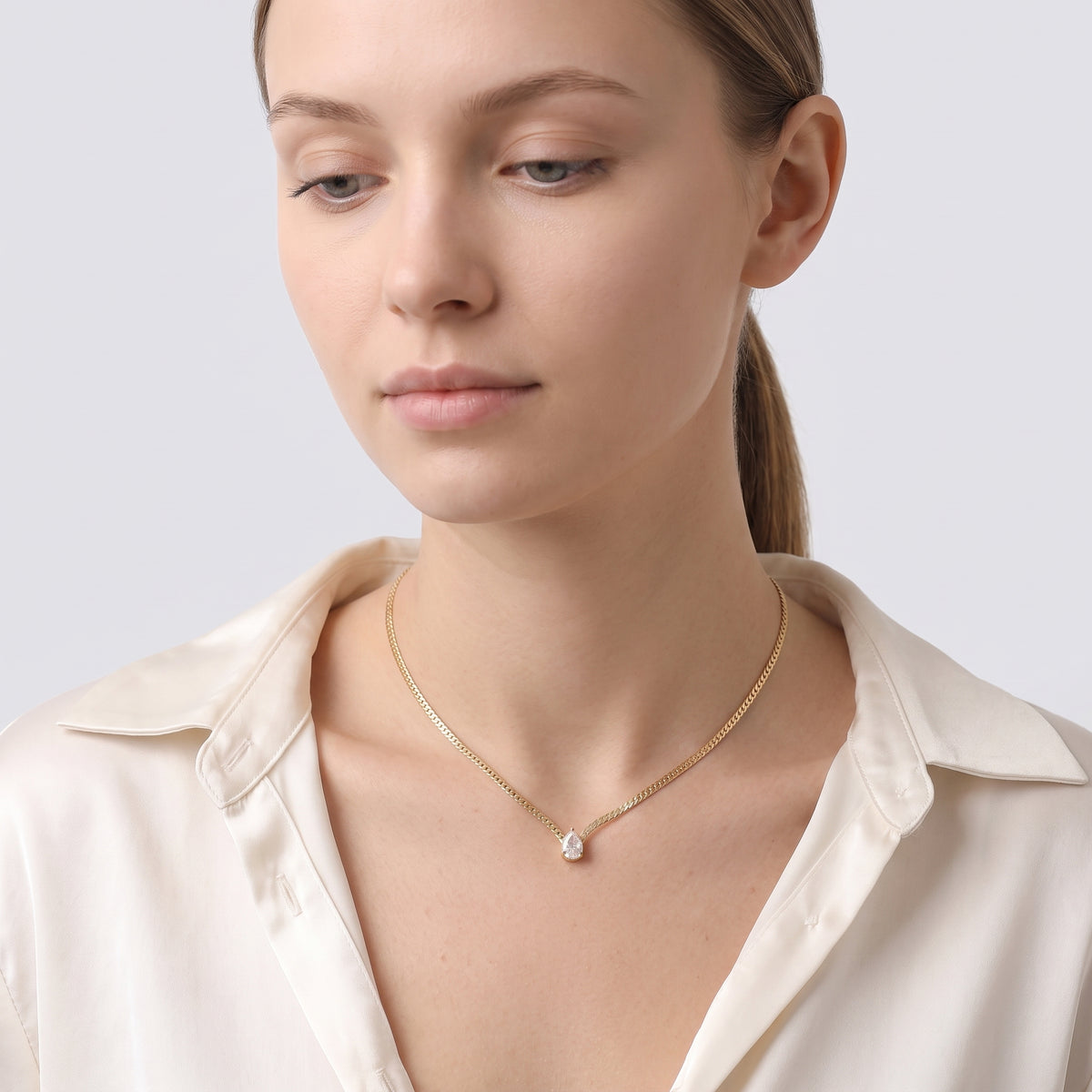 Woman looking down at the Teardrop Bezel Necklace