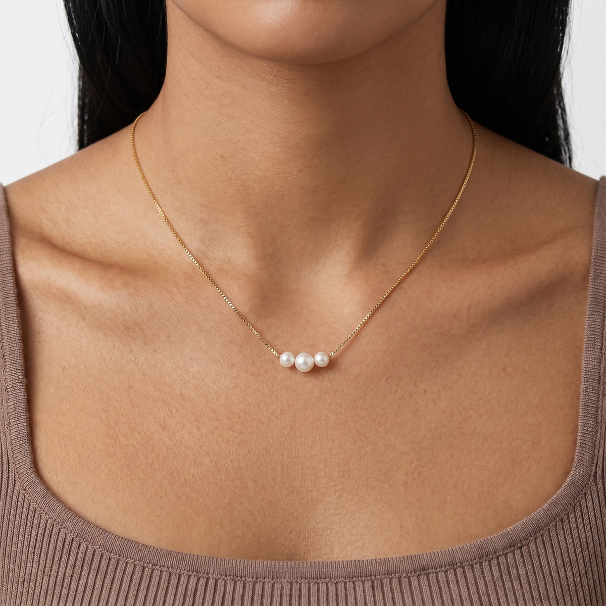 Close-up of the Lelice Trinity Pearl Necklace in gold at the collarbone