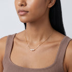 Woman turned three-quarters wearing the Trinity Pearl Necklace