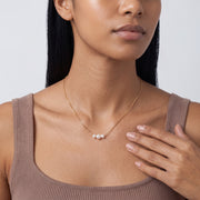 Hand at the collar of a woman wearing the Trinity Pearl Necklace