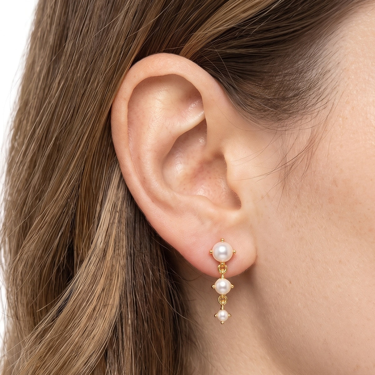 Close-up of the Lelice Trinity Pearl Drops in gold on the ear