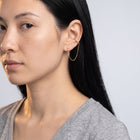 Model wearing the Lelice Victoire Chain Earrings in gold, turned toward the light