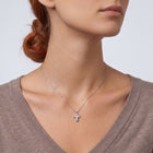 Low-angle portrait of a woman wearing the Zara Cross Necklace
