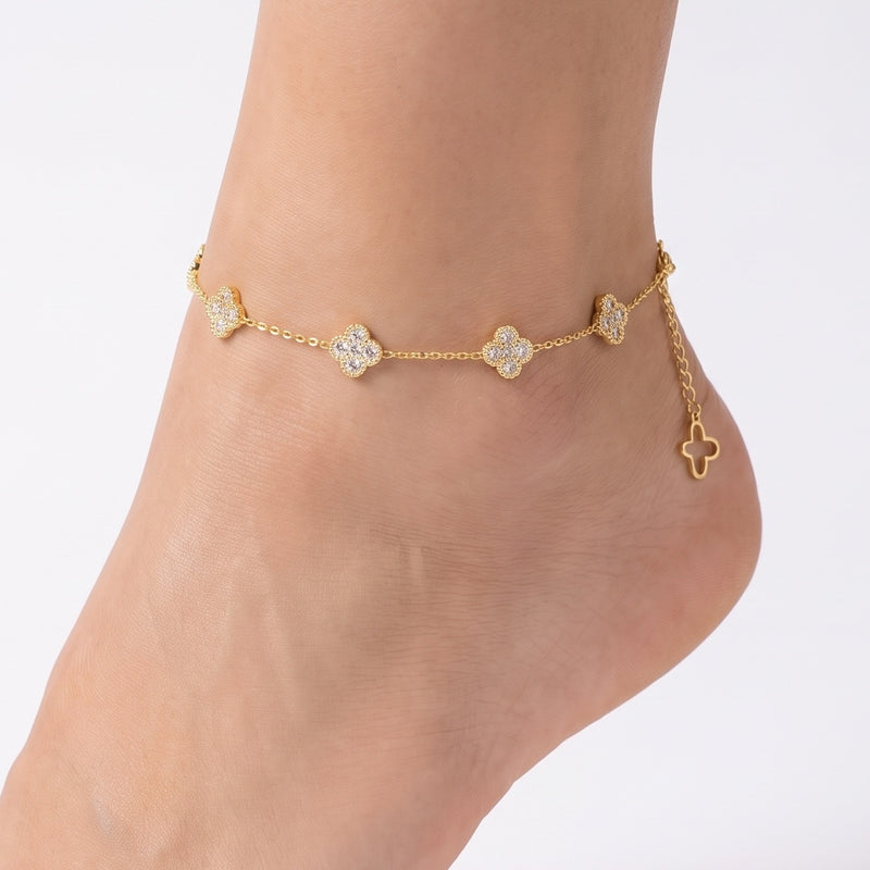 Close-up of the Lelice Zaria Crystal Clover Anklet in gold on a woman's ankle